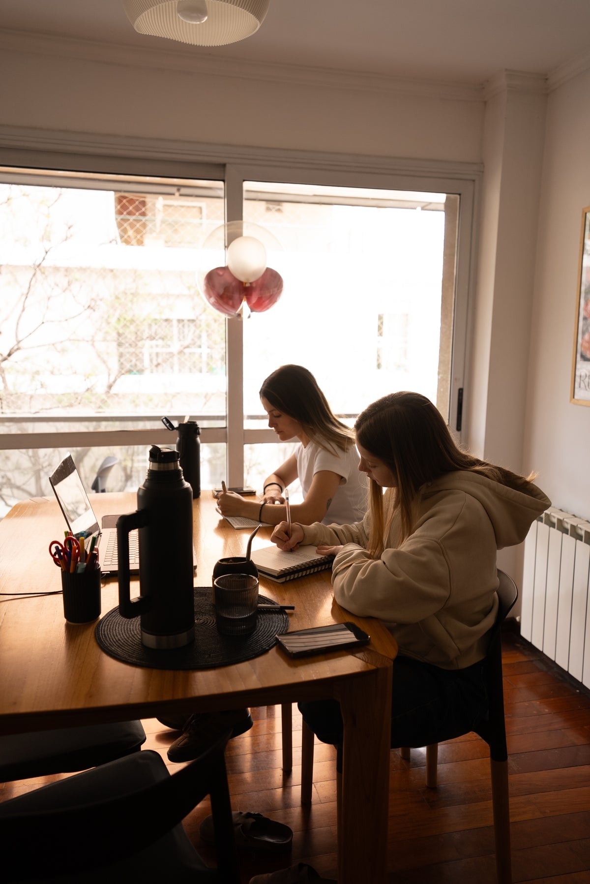 Un cuaderno abierto y una mano escribiendo junto a una bebida